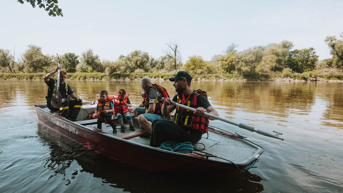 Family enjoying a peaceful day on a lake in a rowboat with life vests.